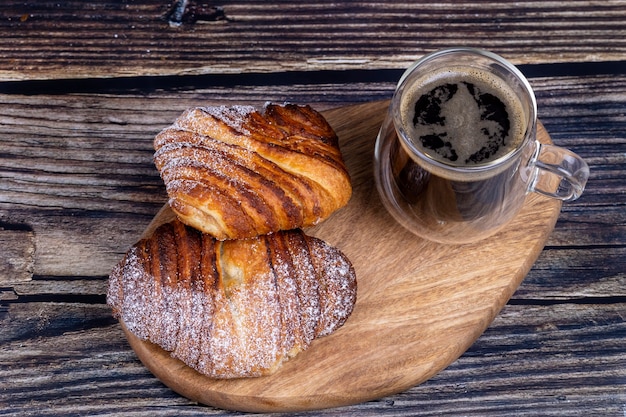 Pãezinhos doces com uma xícara de café em uma placa de madeira