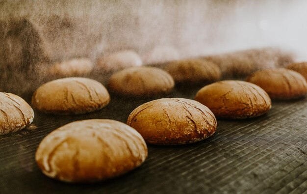 Foto pãezinhos frescos do forno transportador com pão cozer pão oficina de produção de pão pão branco no forno pães quentes doçaria