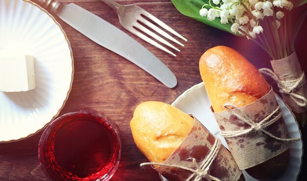 Pãezinhos frescos para o café da manhã. Bun com manteiga para uma xícara de café da manhã. Café da manhã no hotel pães chá de geléia e um buquê de flores.