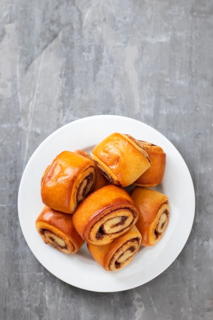 Pãezinhos pequenos com canela em prato branco sobre fundo de cerâmica