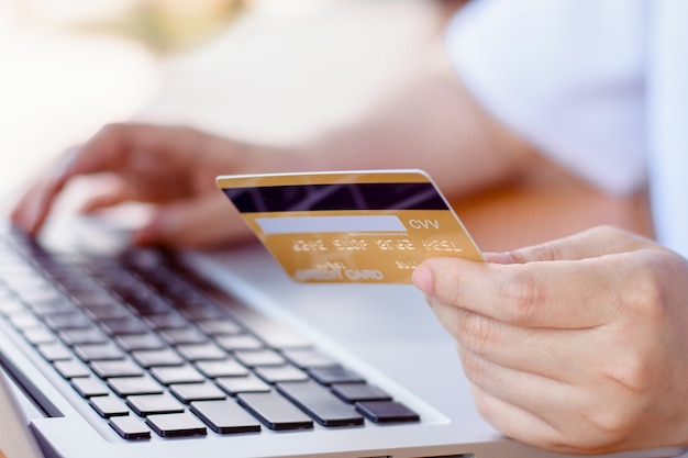 Pagamento online . Mulher com as mãos segurando um cartão de crédito e usando o laptop. Compras online