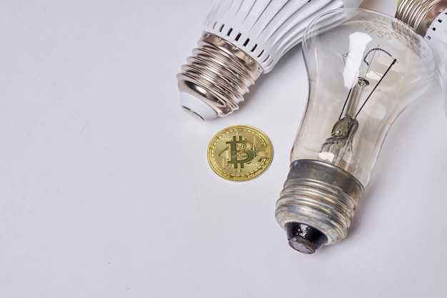 Pagar pela eletricidade com lâmpadas elétricas bitcoin criptomoeda e bitcoin dourado em branco