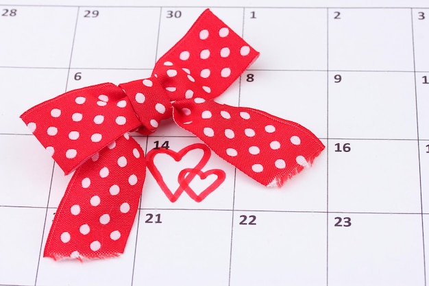 Página de calendario con corazones y lazo en el día de San Valentín
