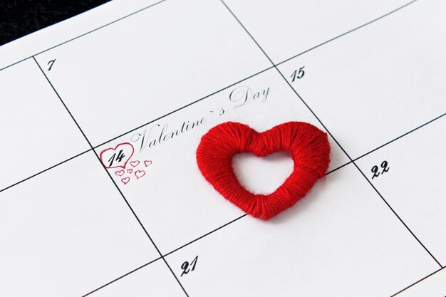 Página del calendario con corazones rojos el 14 de febrero, día de San Valentín sobre un fondo negro.