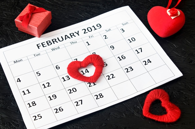 Página del calendario con corazones rojos y un regalo el 14 de febrero.