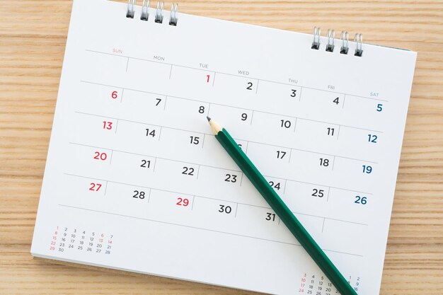 Página de calendario con lápiz sobre fondo de mesa de madera