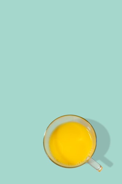 Foto página de portada con un vaso lleno de jugo de naranja recién hecho de frutas frescas en fondo turquesa sólido con espacio de copia concepto de vitaminas de alimentos saludables y vida saludable