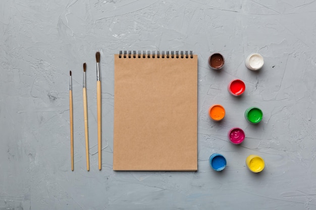 Páginas do álbum e pincel de lápis de tinta em um fundo colorido vista superior com espaço vazio no local de trabalho para desenho de conceito de ensino em casa de criatividade