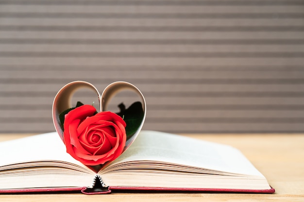Páginas de libro en forma de corazón curvo con rosa roja.