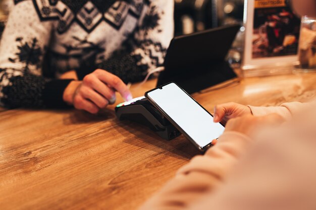 Pago sin efectivo con NFC y teléfono en una terminal de café