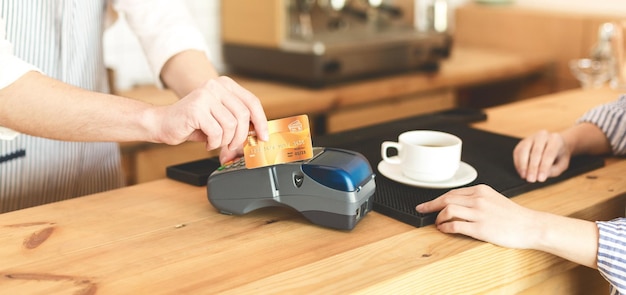 Pago Fácil. Primer plano de pago con tarjeta dorada en terminal en línea en café, panorama