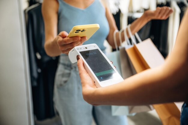 Pago inalámbrico Una mujer está pagando por ropa en la tienda minorista
