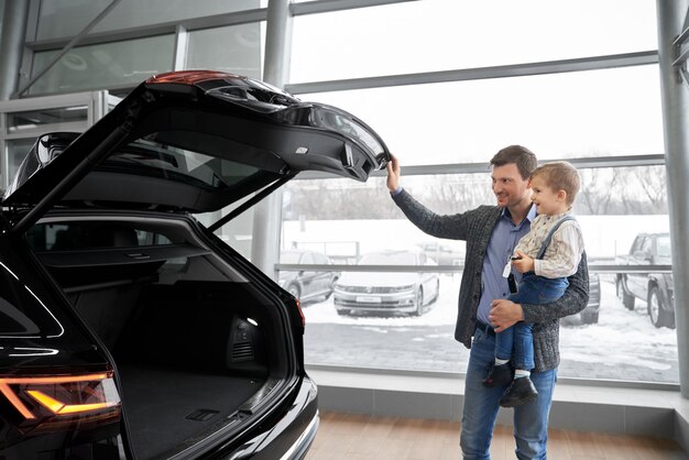 Pai abrindo a mala do carro, mostrando o auto para o filho.