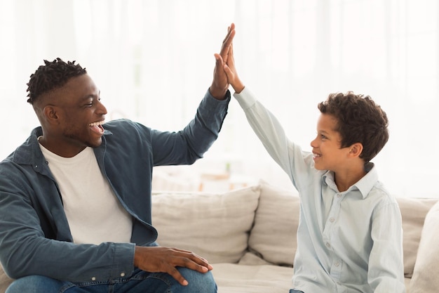 Pai africano e garoto dando mais cinco em casa