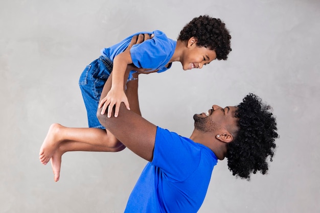 Pai afro e filho negro em fundo cinza sorrindo e feliz pai afro no dia dos pais dia dos pais em agosto