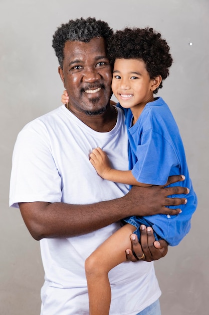Foto pai afro e filho negro em fundo cinza sorrindo e feliz pai afro no dia dos pais dia dos pais em agosto
