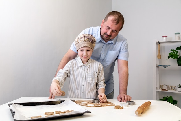 Foto pai ajuda o filho a fazer biscoitos para o feriado