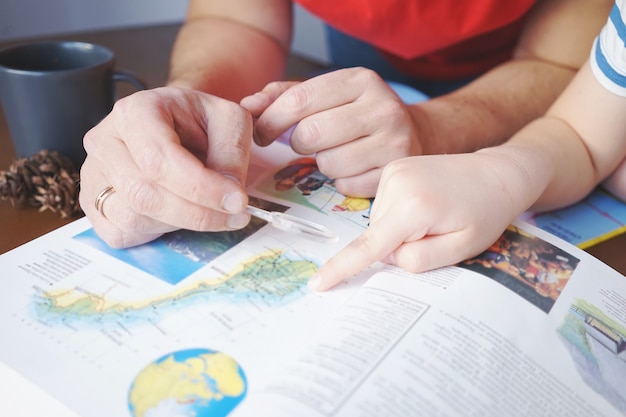 Foto pai ajuda o menino a aprender geografia com uma lupa