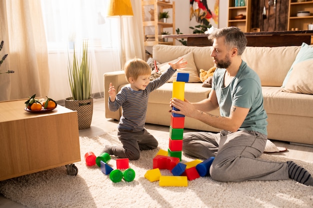 Foto pai, ajudando o filho a construir torre de cubos