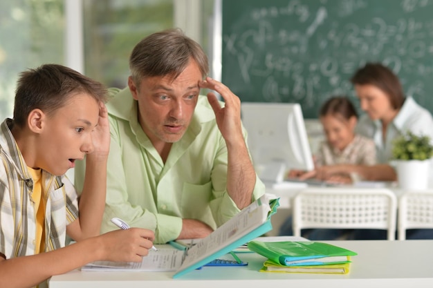 Pai ajudando seu filho fazendo lição de casa em sala de aula