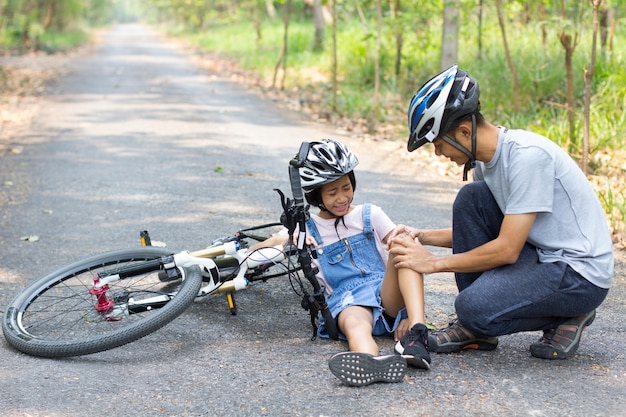 Pai ajudou a filha a cair de bicicleta. Andar de bicicleta na rua.