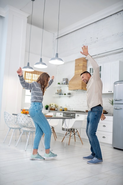 Foto pai alegre e despreocupado com a filha dançando em casa na cozinha.