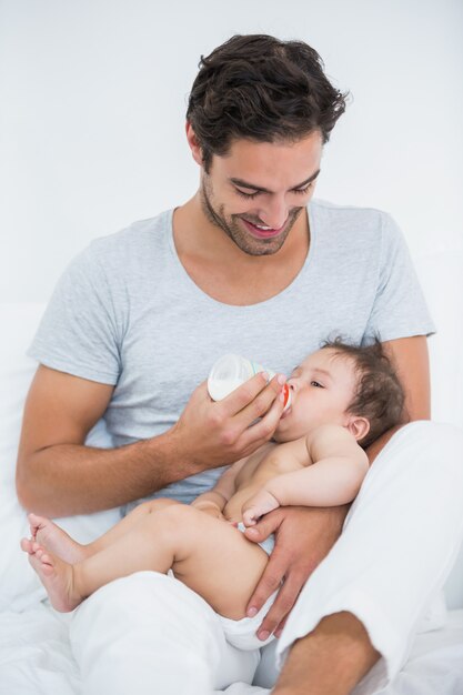 Pai alimentando o leite para a filha em casa