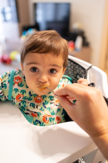 Pai alimentando seu bebê com comida sólida, seus primeiros purês de vegetais