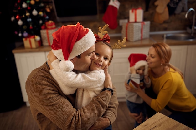 Pai amoroso beijando sua filha enquanto comemora o Natal em casa