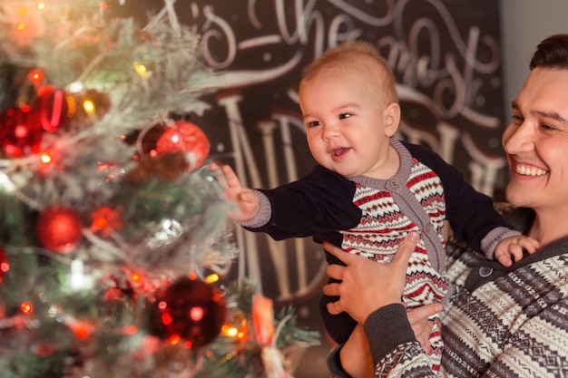 Pai amoroso com filho perto da árvore de Natal sorrindo juntos