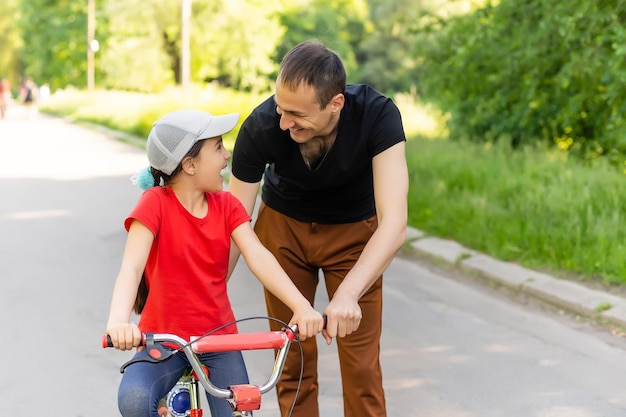 pai amoroso ensinando a filha a andar de bicicleta.