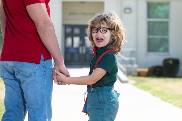 Pai andando com o filho para o pai da escola e aluno da escola primária com retrato de mochila de