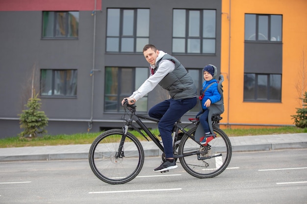 Pai andando de bicicleta com filho no banco da bicicleta