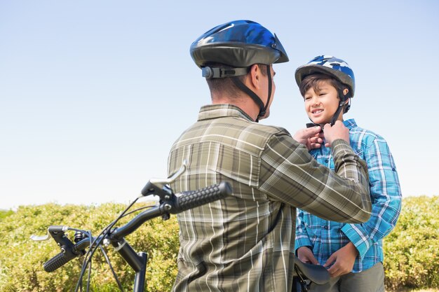 Pai anexando seu filho capacete de ciclismo