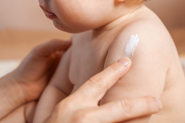 Pai aplicando creme corporal em seu bebê