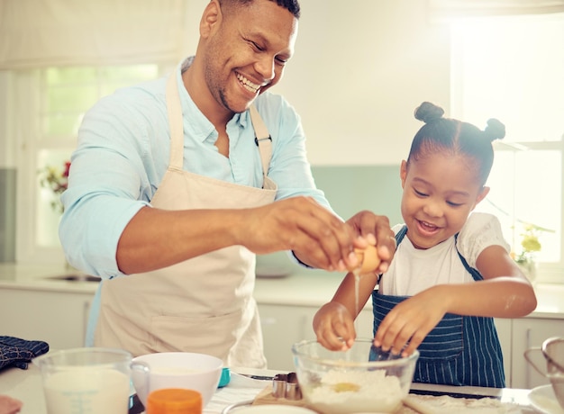 Pai aprendendo menina ou assando na cozinha de casa e cozinhando um bolo infantil sobremesa ou biscoitos de café da manhã Criança feliz e cômica divertida com sorriso em casa com homem de família com ovo de comida saudável