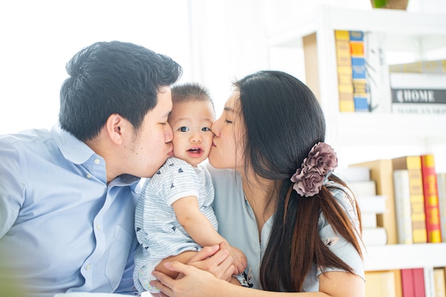 Pai asiático beijando seu bebê em casa.
