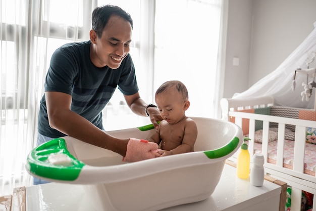 Pai asiático dando banho para sua criança bebê