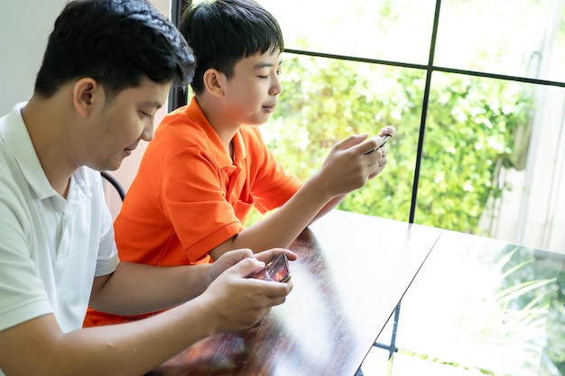 Pai asiático e filho com celular jogando juntos pai passam tempo com a família dos filhos