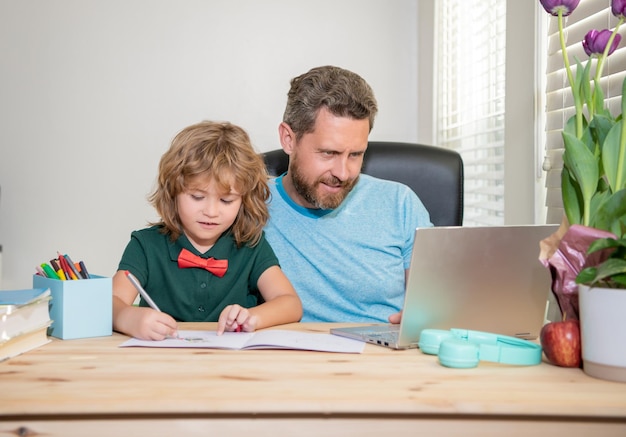 Pai barbudo ou professor particular da escola ensinando filho menino com lição de laptop moderno online