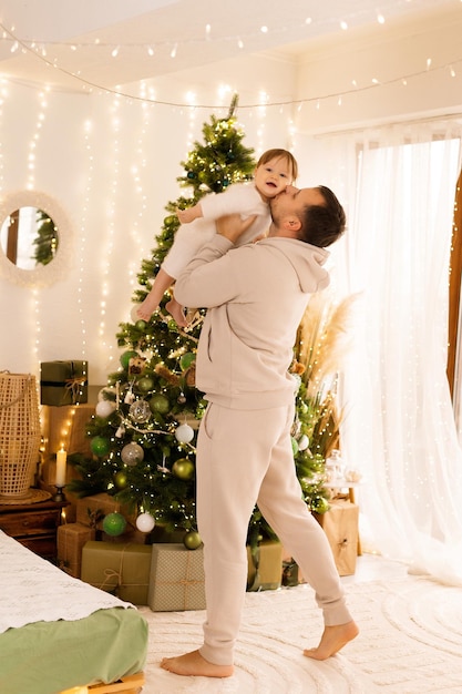 pai beijando a criança no fundo da árvore de Natal