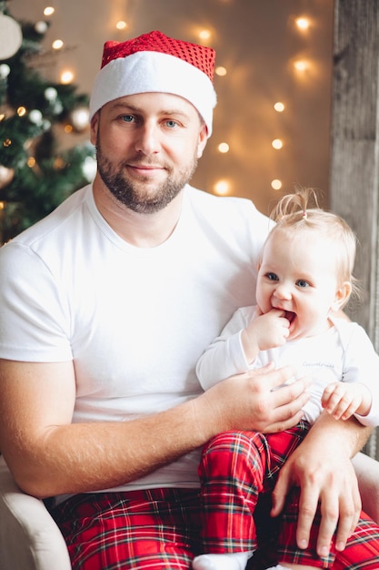 Pai bonito e jovem segurando um bebê de joelhos em clima de natal