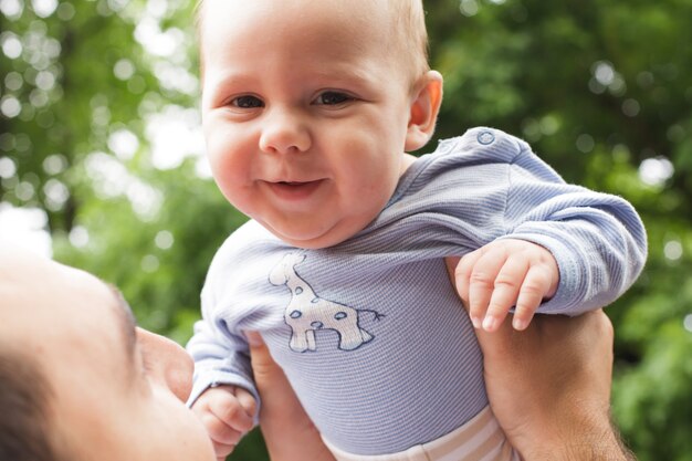 Pai brinca com filho em um parque. Bebê voador