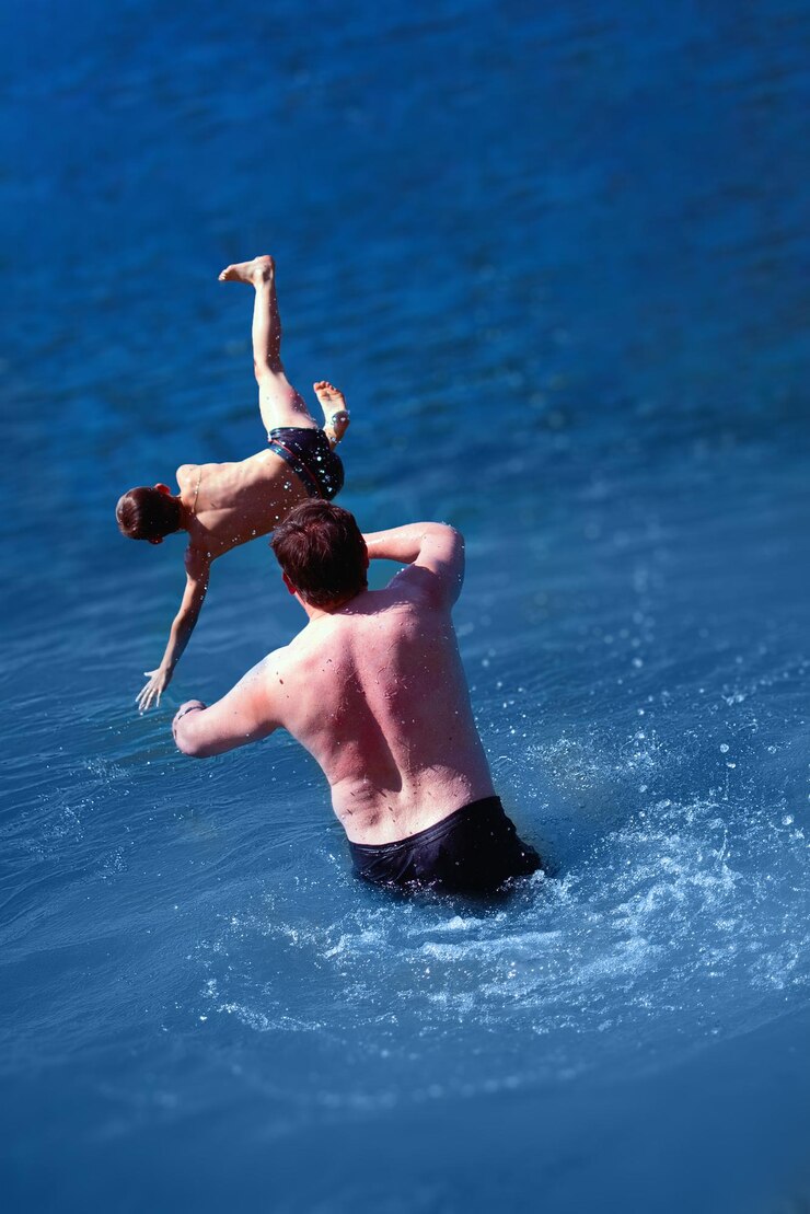 Foto pai brinca com o filho na água do mar pai joga o bebê enquanto nada no mar