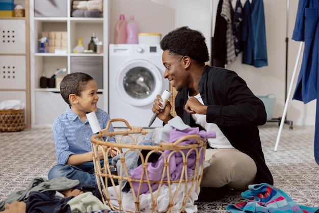 Pai brincando com o filho enquanto limpava fazendo tarefas domésticas homem cantando para limpar rolo