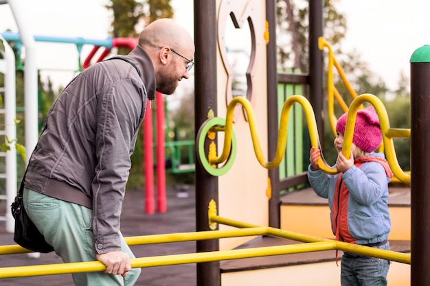 Pai brincando com seu filho no playground moderno, família alegre se divertindo andando