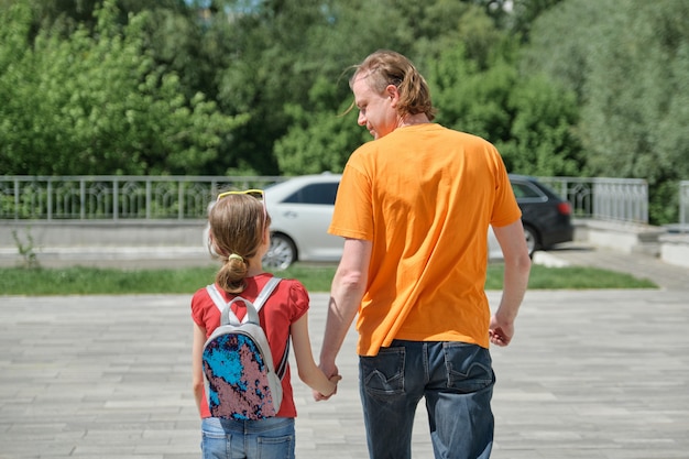 Pai caminha com sua filha de mãos dadas