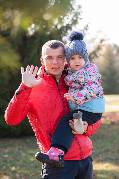 Pai caminhando com a filha nas mãos