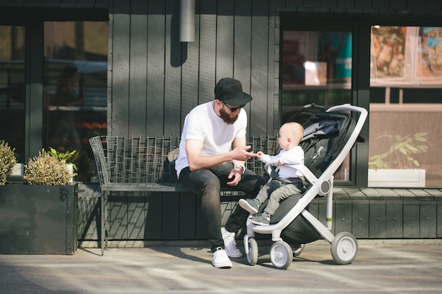 Pai caminhando com um carrinho e um bebê nas ruas da cidade