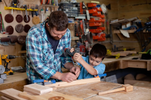 Pai carpinteiro e filho menino trabalham na oficina Pai mestre ensina seu filho carpintaria Continuidade